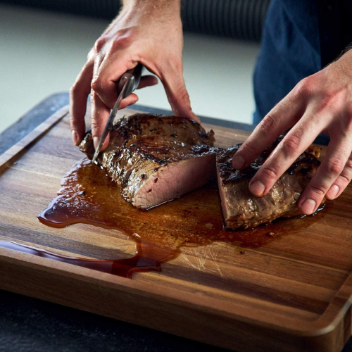 Een houten snijplank met sapgeulen voor het snijden van vlees